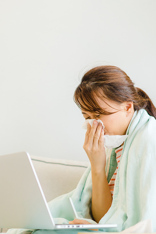 Woman sneezing into a Kleenex with allergies