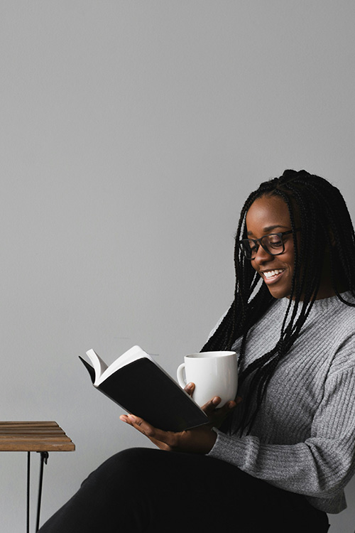 Black woman sitting at a table smiling and reading a bible