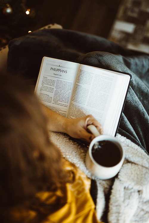 Woman holding a coffee cup and a reading Bible verses to read in the morning