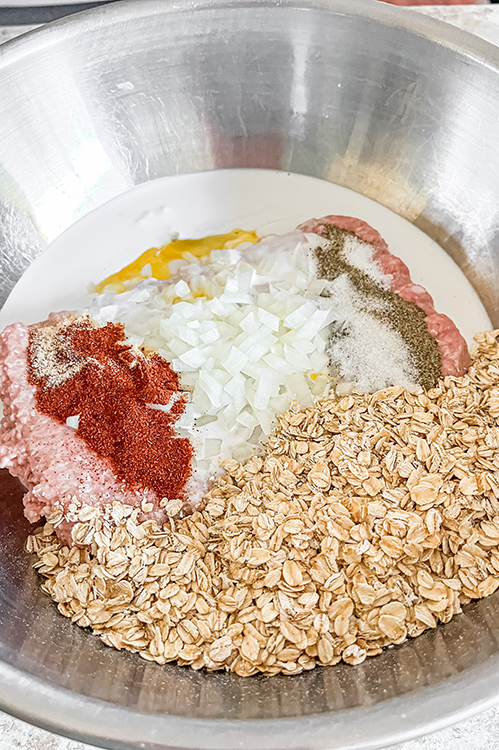 All Meatloaf ingredients in a large silver mixing bowl