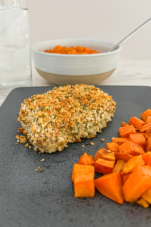 breaded oven baked pork chops after cooking, with a side of cubed sweet potato