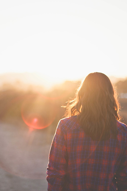 woman in a plaid shirt at sunset walking on a road, for bible verses on identity and purpose blog post