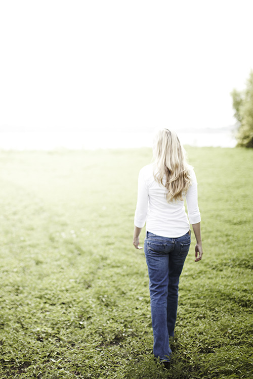 young woman with long blonde hair walking in an open field, for bible verses on identity and purpose blog post